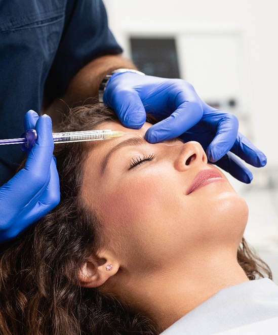 a woman receiving a BOTOX injection above her eyebrow